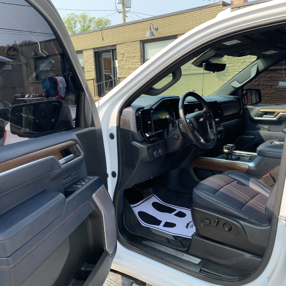 A fabric seat getting vacuumed and cleaned by a car detailer.