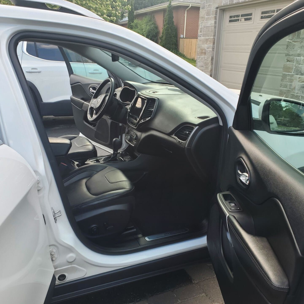 The interior of an all black mercedes-benz that has recently been detailed. The vehicle has an all black finish with red stitching throughout the leather.