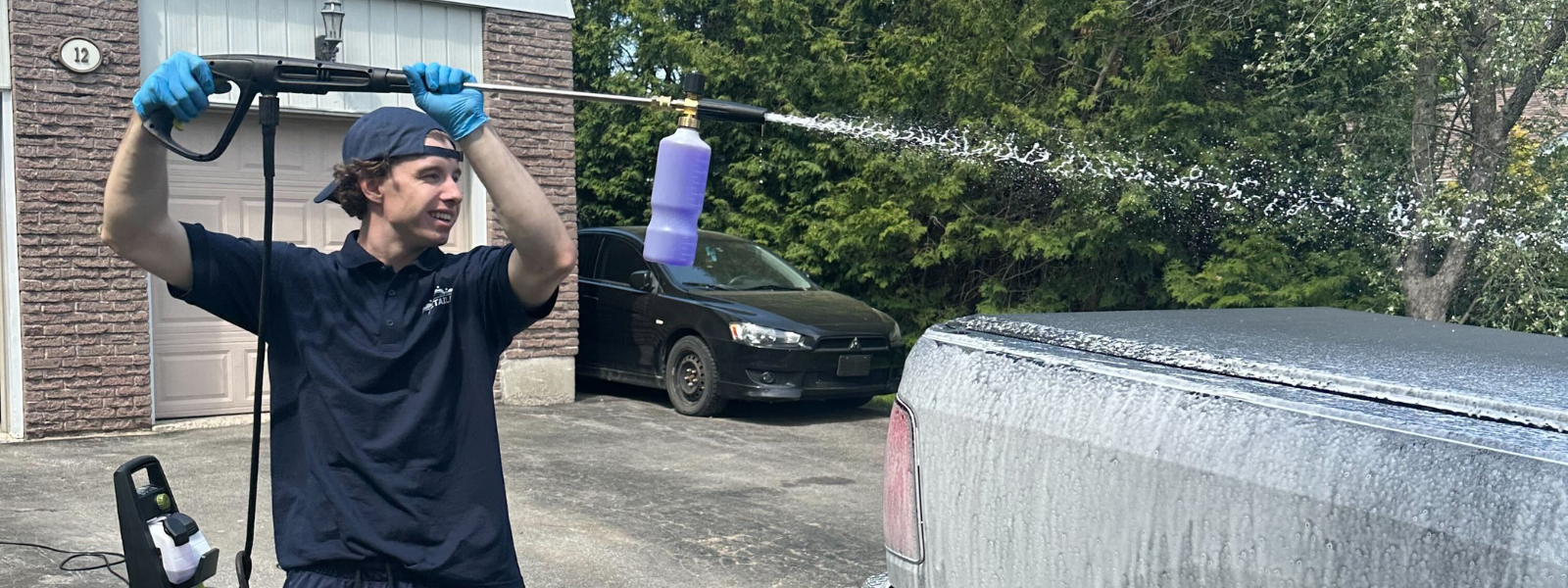 the detaild team washing a truck using a pressure washer