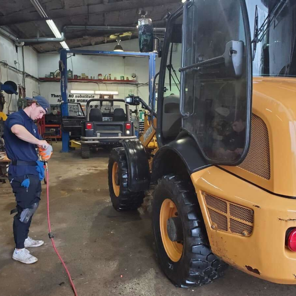 A person detailing a fork lift